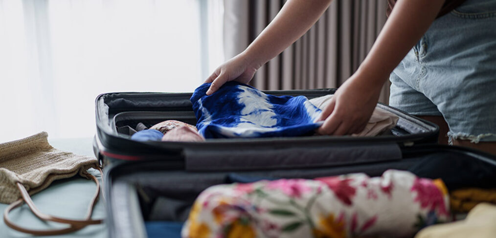 Woman checking suitcase prepare for travel at her bedroom
